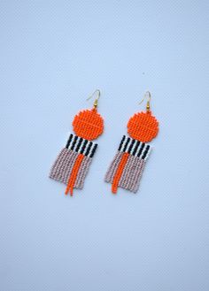 an orange and black beaded earrings with fringes on it's ear ends