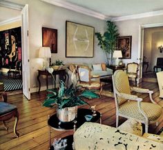 a living room filled with lots of furniture and paintings on the wall above it's doorway