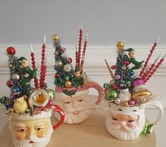 three coffee mugs decorated with christmas decorations and santa claus's head on top