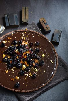 a chocolate dessert with berries and nuts on top, next to the letter u spelled out