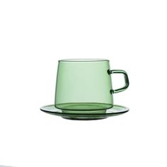 a green cup and saucer sitting on top of a glass plate with a white background