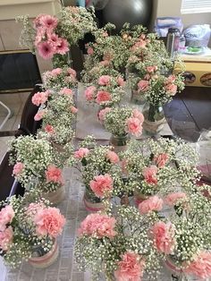 several vases filled with pink and white flowers on top of a table covered in paper