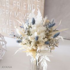 a vase filled with white and blue flowers sitting on top of a table next to a sign