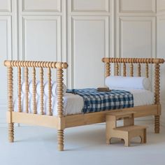 a wooden bed with a checkered blanket next to a step stool in front of it