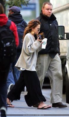 a man and woman are walking down the street with their cell phones in their hands