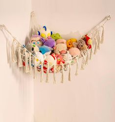 a hammock filled with stuffed animals and tassels hanging from the wall