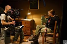 a man sitting in a chair next to a woman with a camera on her lap