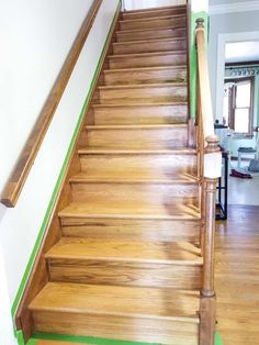 a wooden staircase with green tape on the bottom and handrails leading up to an open door