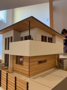 a model of a house on display in a room with two people looking at it