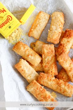 some food is sitting on top of wax paper and next to a bottle of mustard