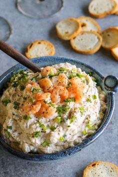 a blue bowl filled with shrimp dip and crackers on top of a gray surface