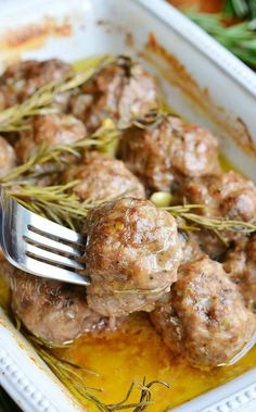 a fork is stuck into some meatballs in a casserole dish with mustard