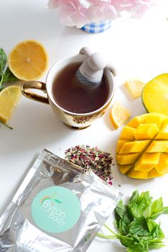 a bag of tea next to some fruit and flowers