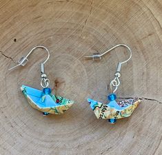 two origami boats are hanging from earrings