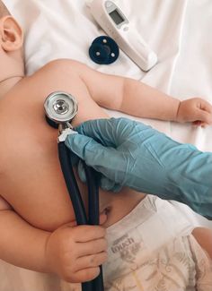 a baby laying on top of a bed with a stethoscope