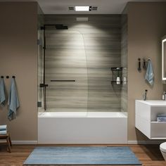 a bathroom with a bathtub, toilet and rugs on the wooden flooring