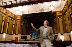 a man standing in an auditorium with his hands up