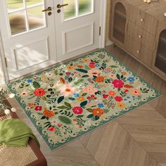 an area rug with flowers and leaves on it in front of a kitchen door, next to a potted plant