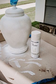 a white vase sitting on top of a table next to a spray bottle