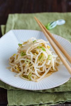 a white plate topped with noodles and chopsticks on top of a green napkin