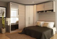 a bed sitting in a bedroom next to a tall white wall mounted cabinet and mirror