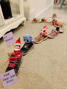 there are several elf dolls sitting on the floor with signs in front of them that read, the shoe shine train