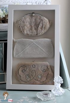 three different purses in a white box on a blue tablecloth with lace doily