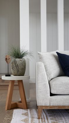 a white couch sitting next to a wooden table on top of a hard wood floor