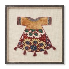 an embroidered dress with tassels and flowers on the chest, framed in a wooden frame