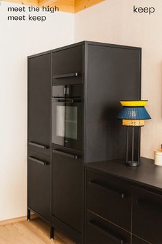 a black cabinet sitting next to a lamp on top of a wooden table in a room