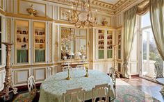 an ornate dining room with chandelier, table and bookshelves on the wall