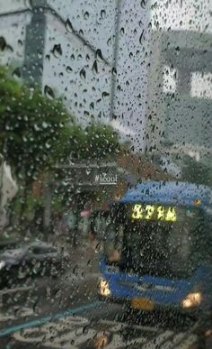 a bus driving down a rain soaked street next to a tall building with lots of windows