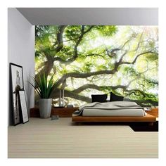 a bedroom with a large tree mural on the wall and bed in front of it