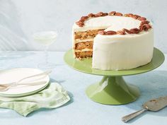 there is a cake with white frosting and pecans on the top, next to two plates