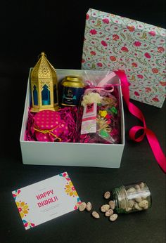 an open gift box filled with lots of goodies next to a card and some nuts