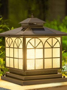 a lamp that is sitting on top of a table in front of some grass and bushes