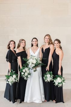 the bridesmaids in black dresses are posing for a photo with their bouquets