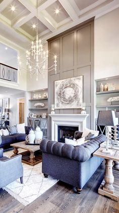 a living room filled with furniture and a chandelier hanging from the ceiling over a fire place