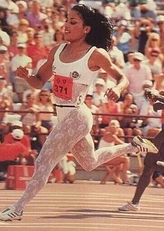 a woman running on a track in front of an audience