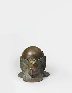 a small bronze object with an animal head on it's face and two eyes