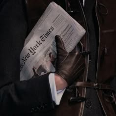 a person wearing gloves is reading a newspaper