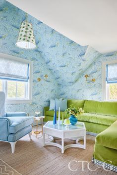 a living room with green couches and blue wallpaper on the walls in it