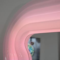 the reflection of a person in a mirror is seen through pink plastic pipes that are lined up on the wall