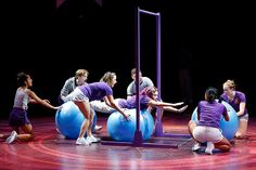 a group of people sitting on top of blue balls in the middle of a stage