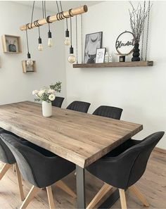 a wooden table with black chairs in a white room