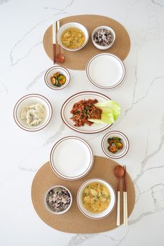 a table topped with plates and bowls filled with different types of food next to chopsticks