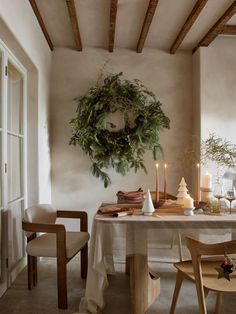 a dining room table with candles and wreath on the wall