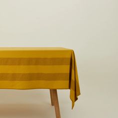 a yellow table cloth with horizontal stripes on it, sitting on a wooden chair in front of a white wall