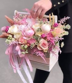 a woman is holding a box with flowers in it