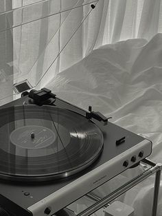 a record player sitting on top of a table next to a white sheet covered wall